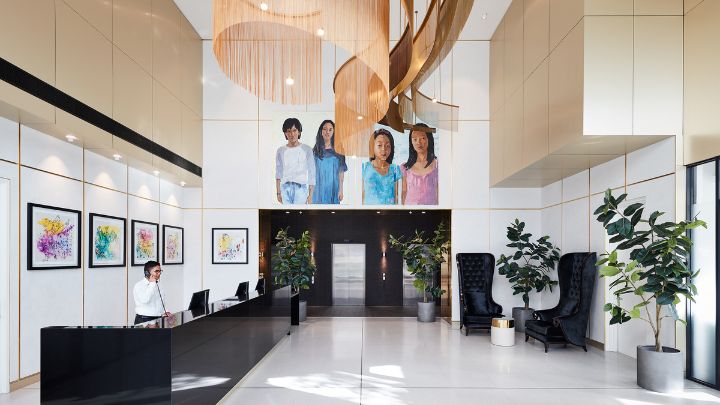A white and black hotel lobby with pastel coloured artwork on the walls